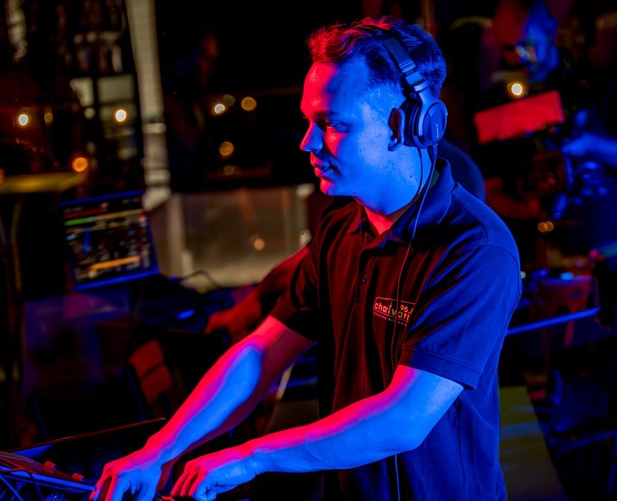 Amadeus Banerjee als DJ auf einer Party. Er ist in atmosphärisches Licht gehüllt.